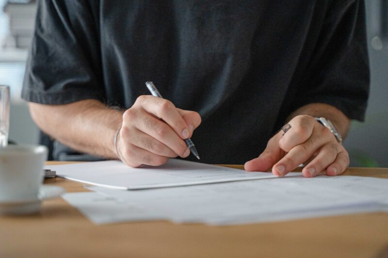 A man writing on a piece of paper with a pen.