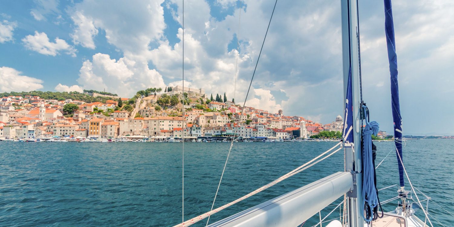 A view of a city from the deck of a sailboat.