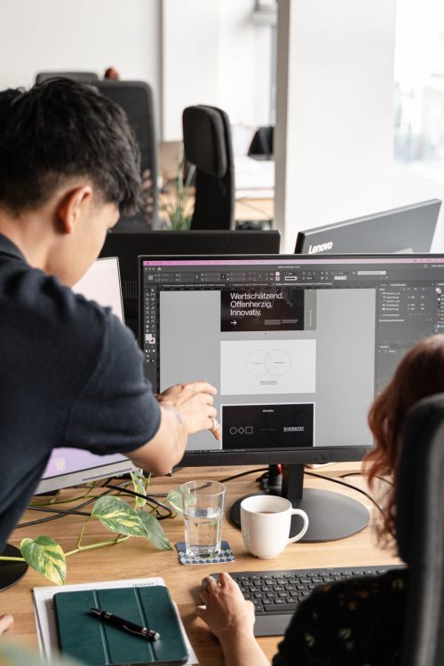 Two people working at a desk in an office.