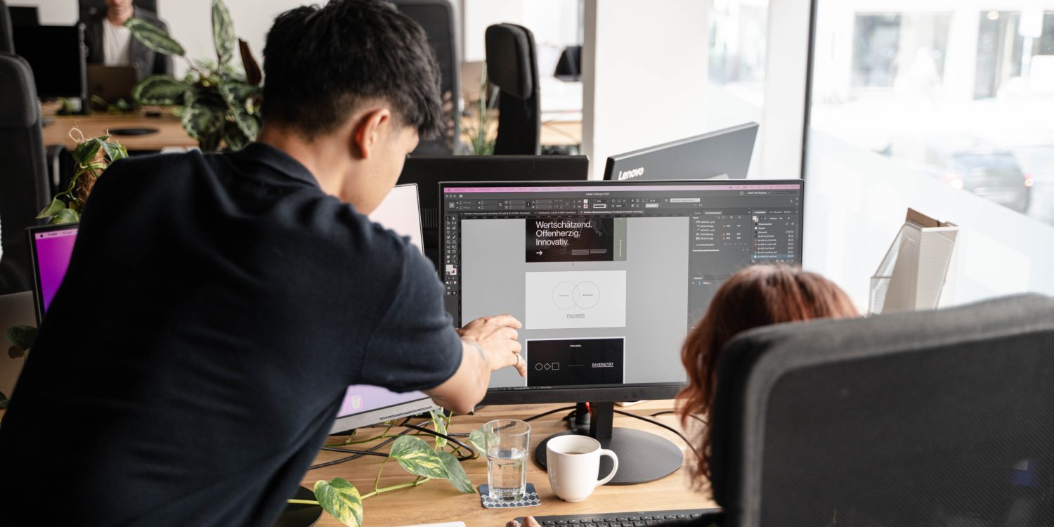 Two people working at a desk in an office.