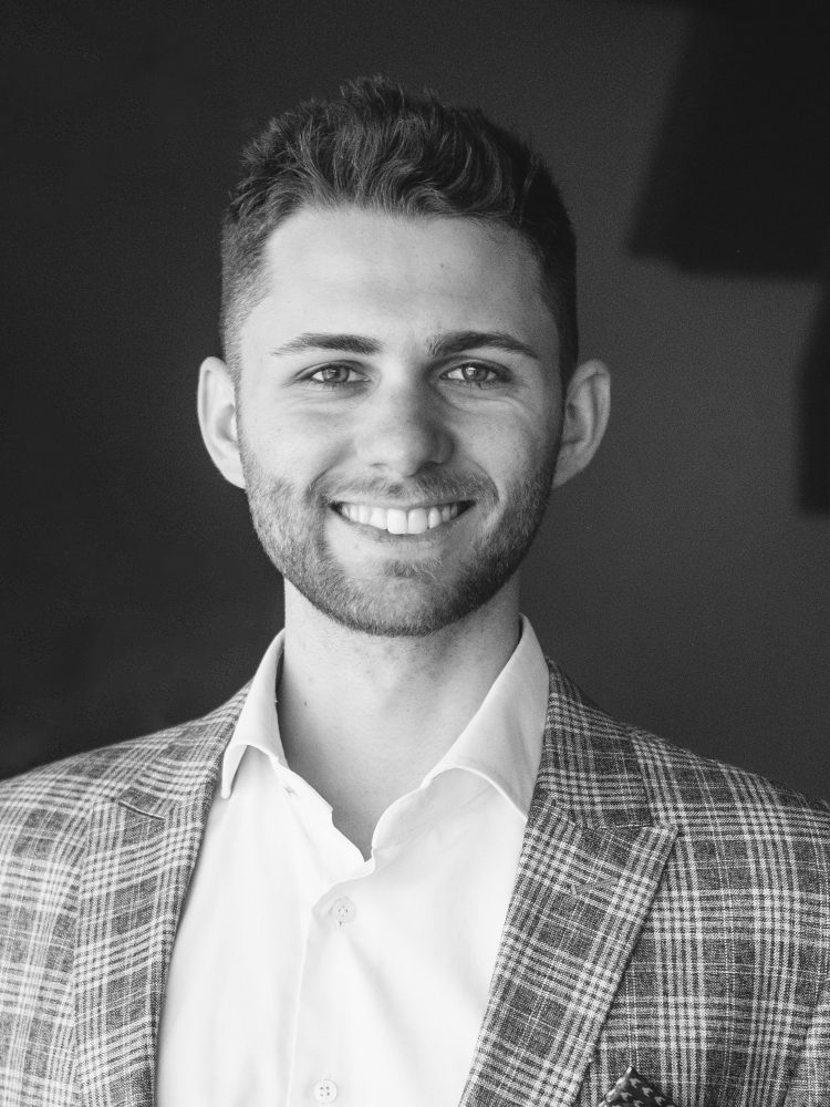 A black and white photo of a smiling man in a suit.