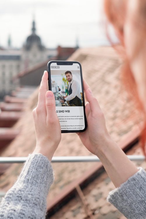 Eine Frau macht mit ihrem Handy ein Foto vom Restaurant Freiblick.